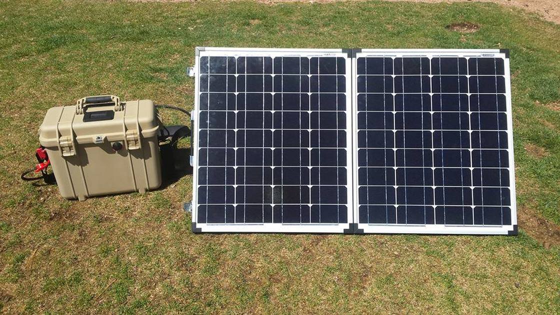 Full system: Pelican case battery bank next to the foldable solar panel, set up outdoors